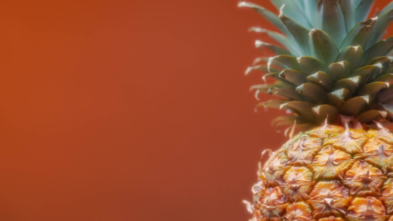 Rotating pineapple on orange background. Slow motion
