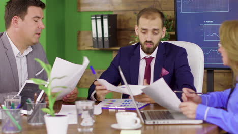 bearded team leader in business suit having a meeting with his investment team