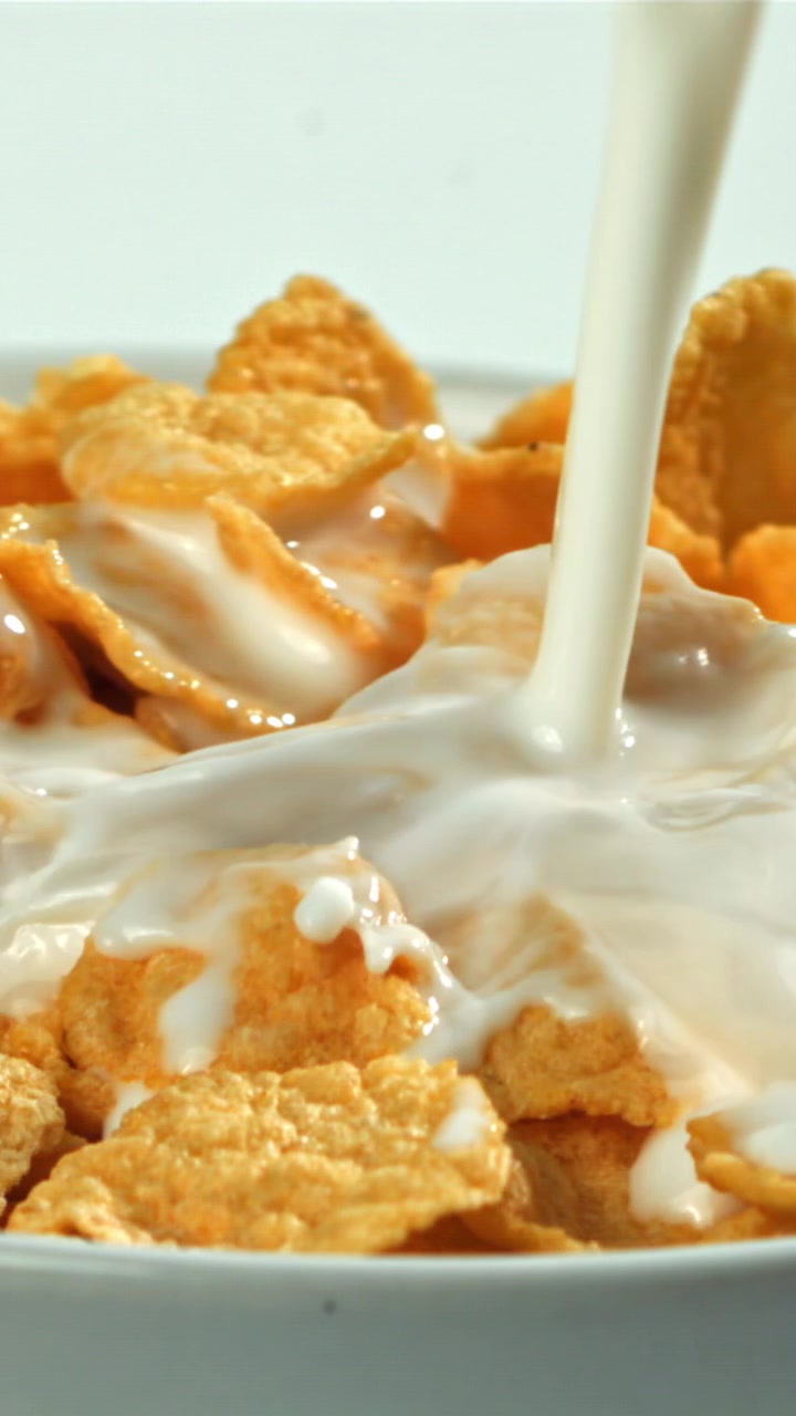 Latte che si versa al rallentatore su cornflakes croccanti