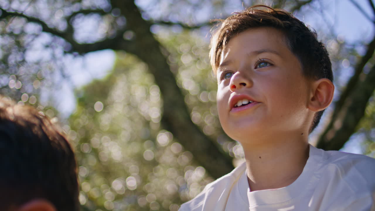 Small kid sitting father shoulders looking sunny nature closeup. Child pointing