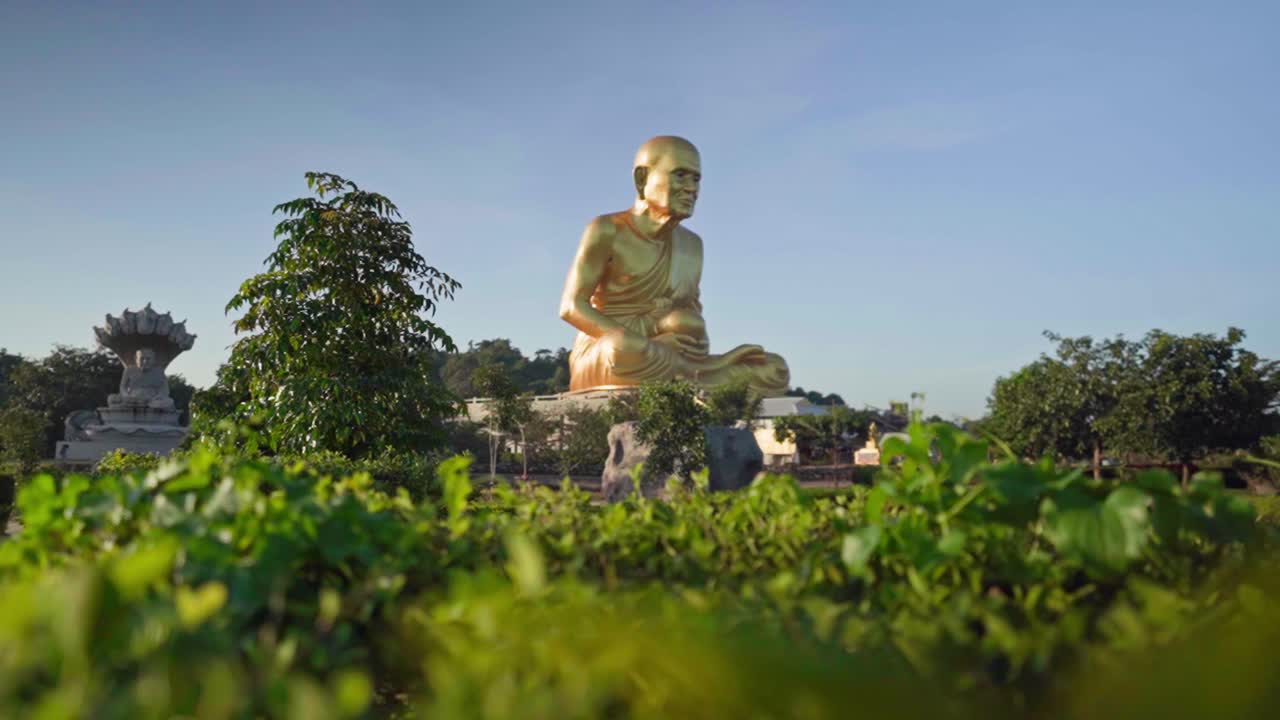 panorámica de 4k sobre la hierba hacia la estatua del monje dorado luang pu thuat