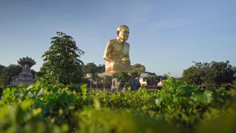 4k pan over the grass towards the golden monk statue luang pu thuat