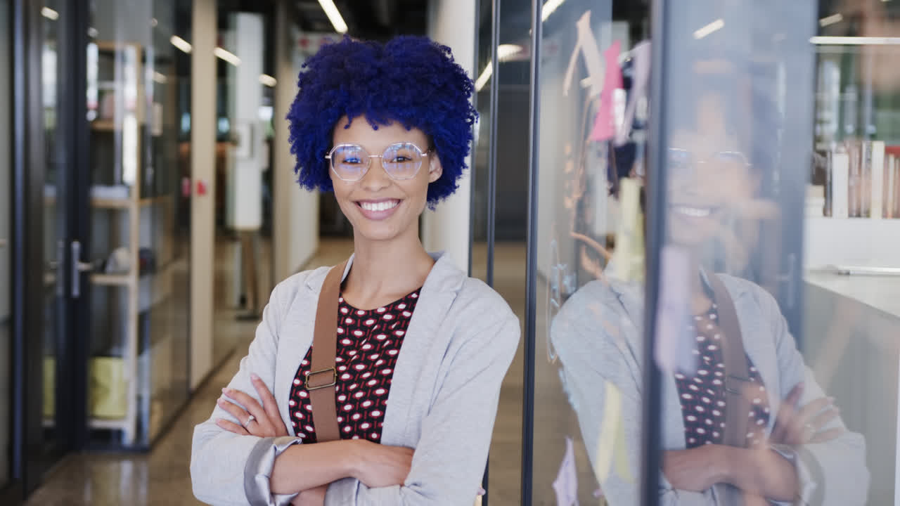 Ritratto di felice imprenditrice birazziale con capelli afro blu in ufficio, al rallentatore.