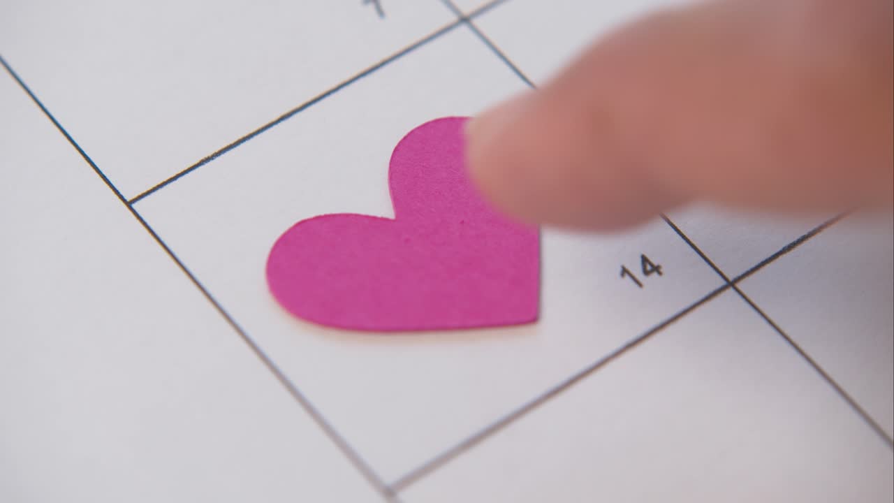 un bonito corazón rosa que se empuja hacia el cuadrado 14 en un calendario