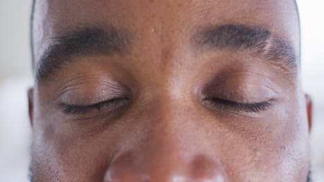 close up portrait of opening eyes of african american man looking to camera, in slow motion