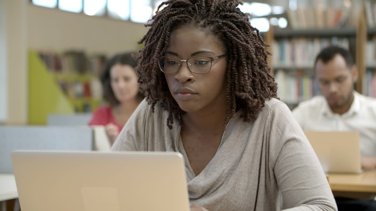 Closeup shot of serious African American woman using laptop