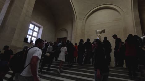 visitors gather around winged victory statue