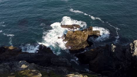 Hermosa-Toma-Aérea-Circular-De-Olas-Golpeando-Una-Roca-En-El-Mar,-Newquay,-Cornwall,-Inglaterra,-Reino-Unido