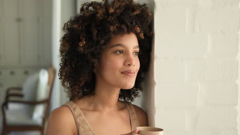 gazing thoughtfully out window, woman sipping coffee at home, feeling relaxed, copy space