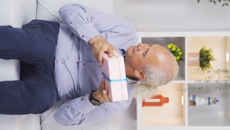 Vertical-video-of-The-old-man-opens-the-gift-box-he-received-from-his-children-and-is-very-happy.