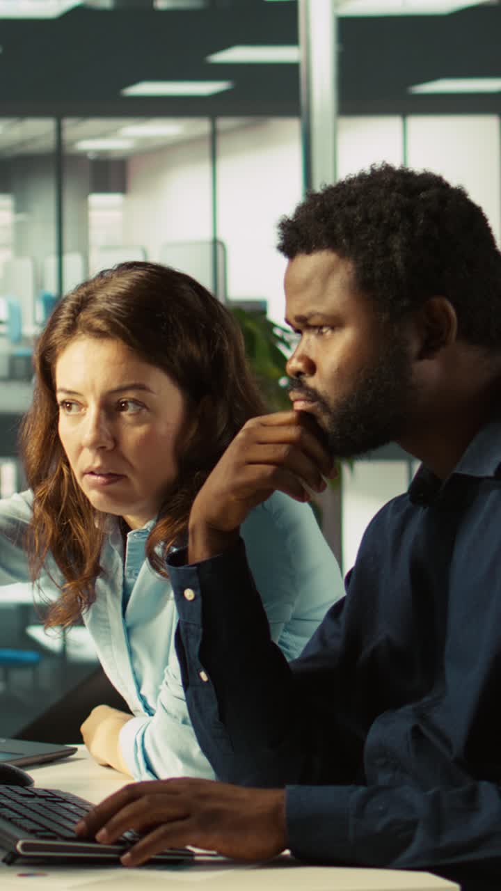 Vertical video Manager supervising work done by accountant inputting financial figures on PC