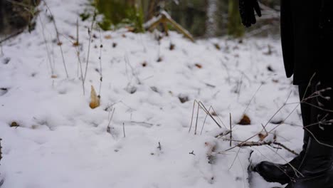 una mujer joven hace bolas de nieve con guantes negros.