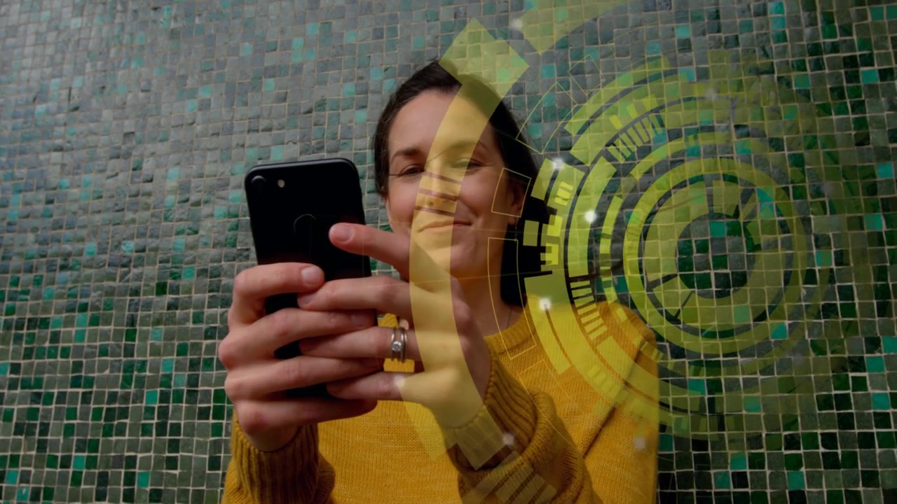 Kobieta w średnim wieku stukająca w smartfon, powodująca nakładkę HUD podczas sprawdzania treści technologicznych na mozaikowej ścianie.