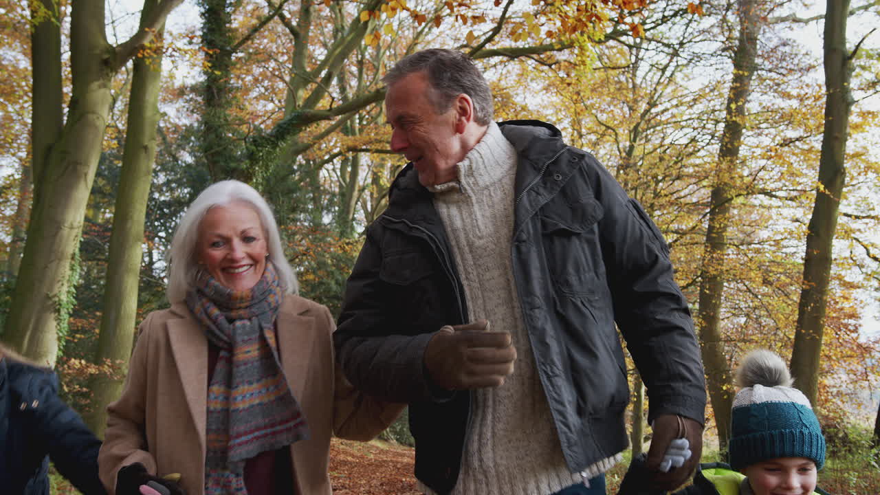 abuelos sonrientes caminando con nietos a lo largo de un camino en el campo de otoño