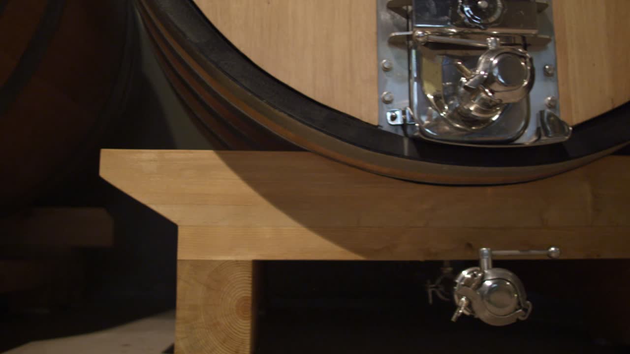 Close up sliding shot of a wooden barrel, inside an italian vinery's cellar to ferment