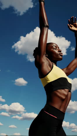 athletic woman stretching and posing under a blue sky