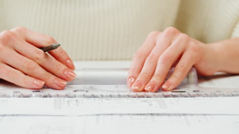 close-up of hands working on blueprints with ruler and pencil