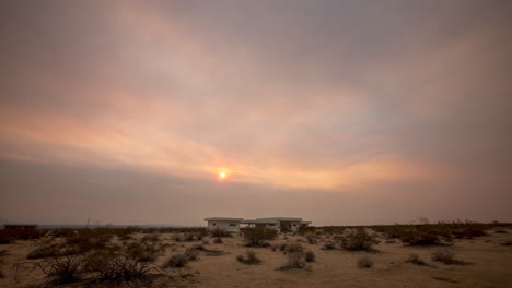 isolated building in a hazy desert landscape with a red sun