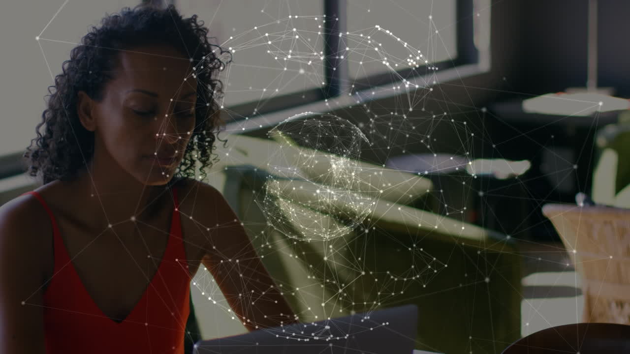 Animation of globe of network of connections over african american woman using laptop at office