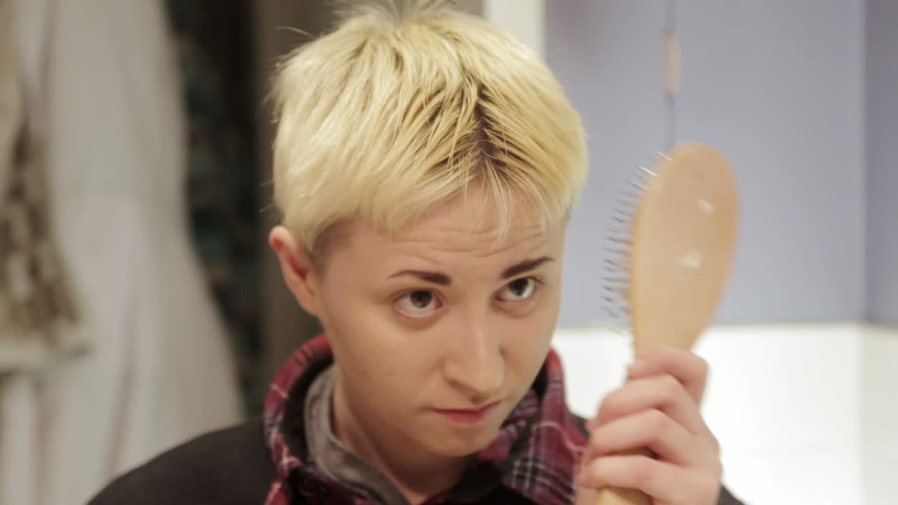 머리를 제대로 빗는 데 어려움을 겪고 있는 단발머리 사람