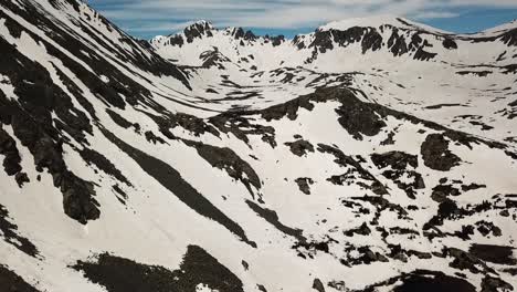 Aerial flight over partially snow covered mountains