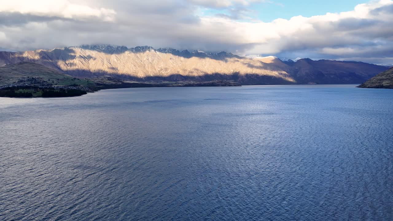 Aerial footage captures the tranquil beauty of Lake Wakatipu surrounded by mountains under soft evening light