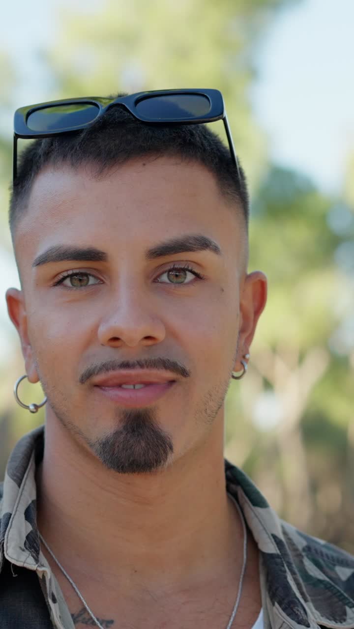 Close-up portrait of a smiling man with sunglasses and earrings