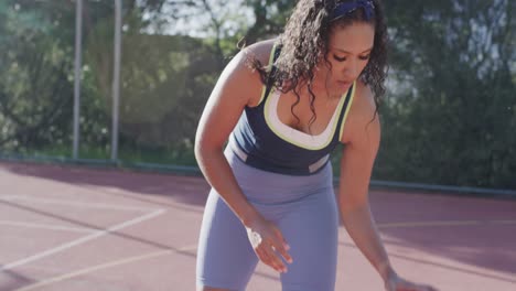 Portrait-of-biracial-female-basketball-player-playing-on-sunny-court,-in-slow-motion