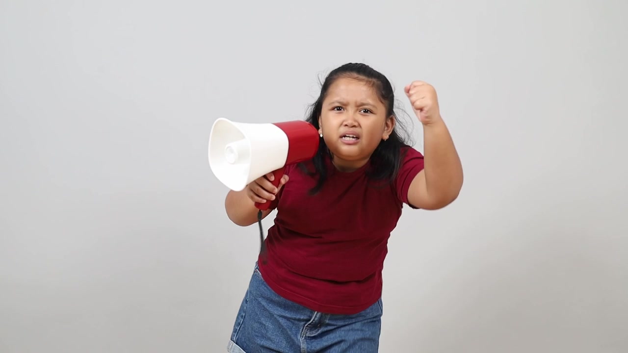 Angry Asian kid holding megaphone while screaming isolated on white
