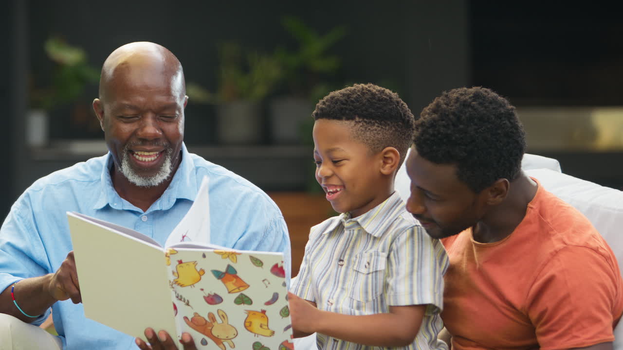Smiling Multi-Generation Male Family Reading Book In Garden Together