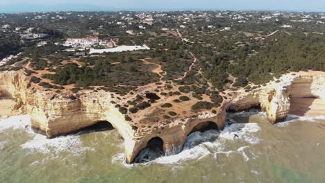 imágenes aéreas de drones en cámara lenta que vuelan hacia una formación rocosa única que se encuentra a lo largo de la costa cerca del pueblo costero de benagil, portugal