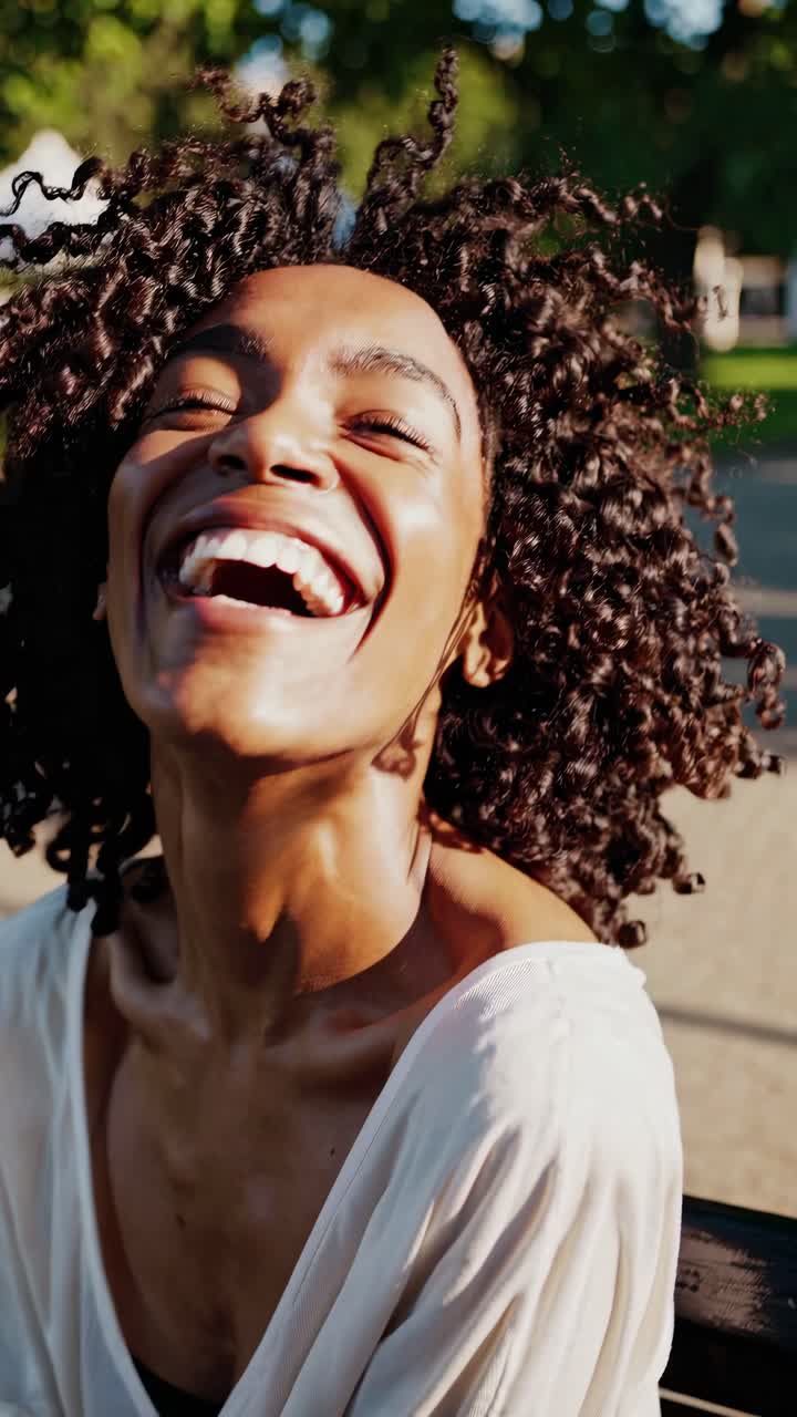 Close-up video still of a person laughing joyfully outdoors, captured at a low angle with a soft