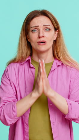 woman pressing palms together in prayer gesture asking please or begging for help with hopeful face