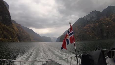 rear view of ship with norwegian flag sailing through the norwegian fjords