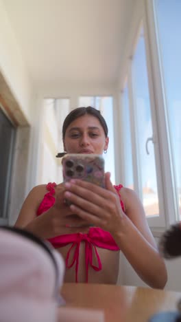 young woman in pink top using a smartphone indoors