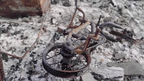 Abandoned-Kid's-Bike-in-the-Middle-of-the-Ash-Remains-of-a-Burnt-Structure---Aftermath-of-Wildfire---4K