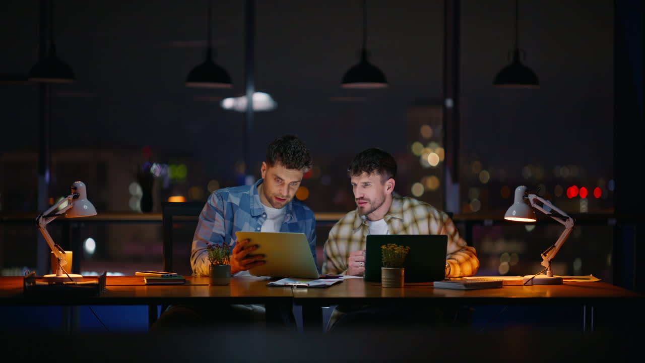 Two designers collaborating evening office. Creative night team planning project