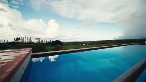 ultra wide slow motion push in of a pool with blue water on a summer day
