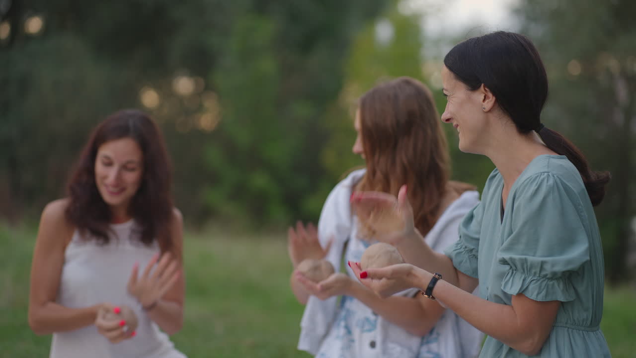 A group of young women in nature in the park conducts a master class on clay modeling. Joint creativity communication laughter common hobby women's circle creative activity.