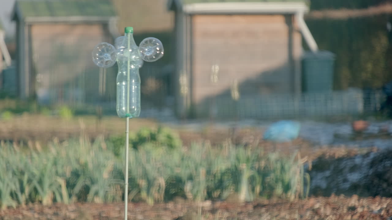 Handcrafted wind turbine spinning in a vegetable garden