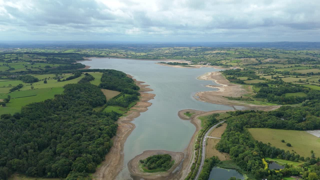 Drone aerial perspective of Carsington Water reservoir during drought with cars on road in countryside Derbyshire Dales United Kingdom