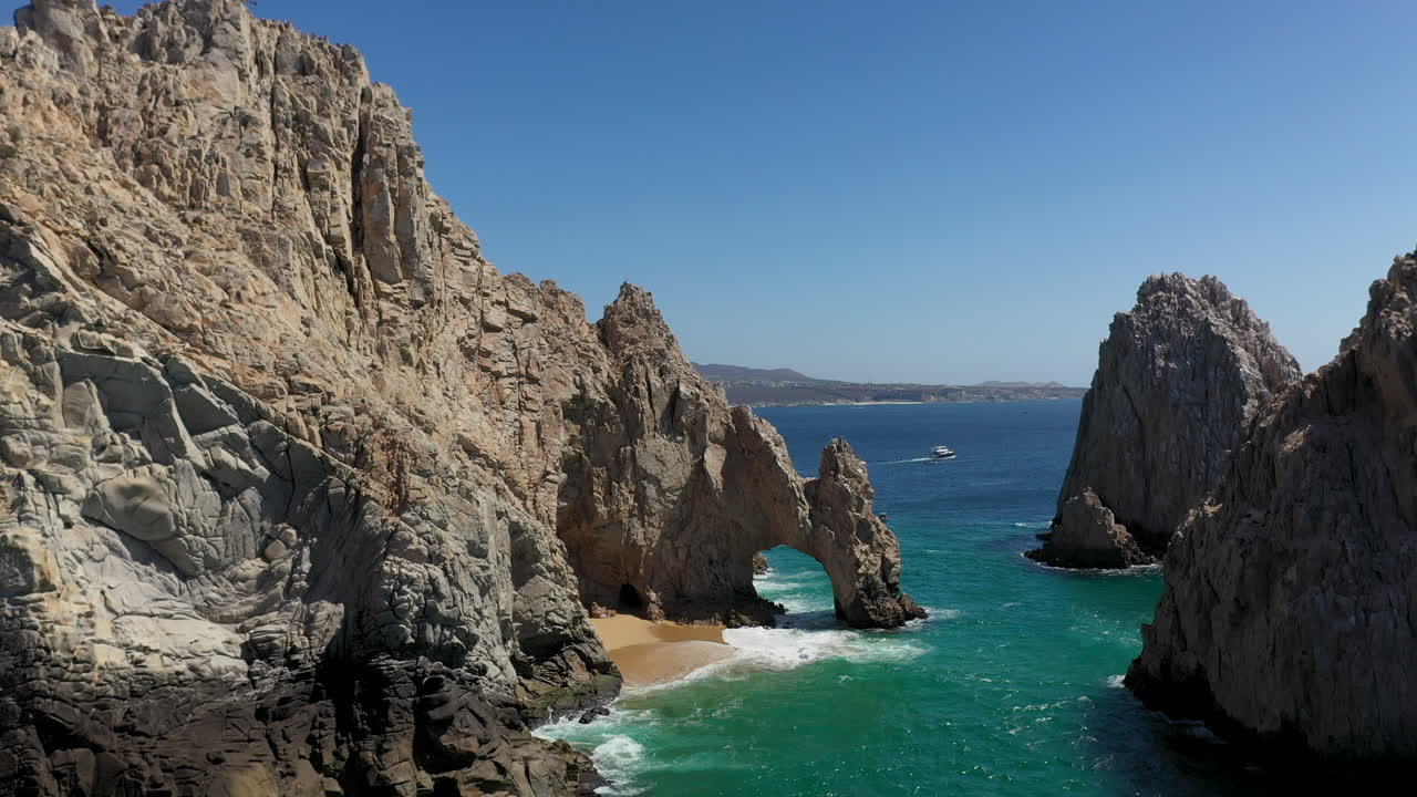 filmación cinematográfica con drones de el arco y luego revelando botes y montañas en cabo san lucas méxico