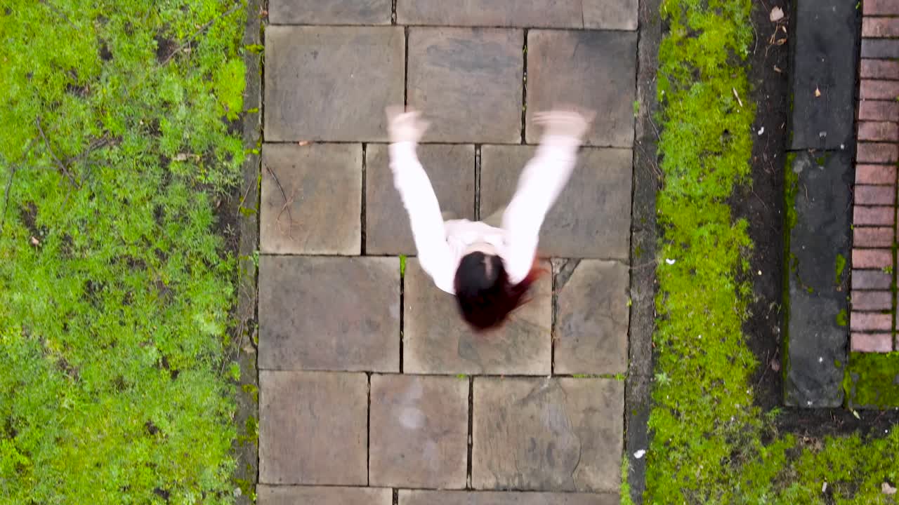 보도 위에서 현대적인 자유형 힙합 댄스를 추는 매력적인 젊은 여성, 하향식 보기