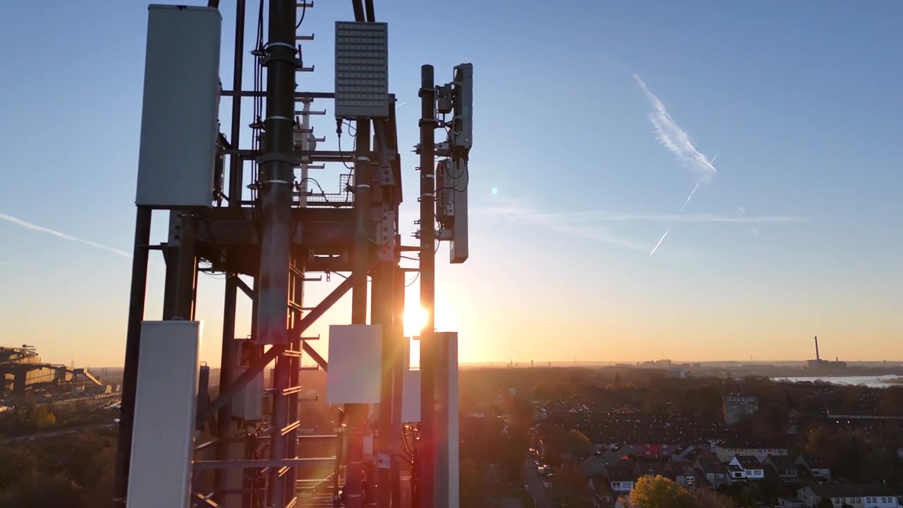 Drone glides left to right beside the tower ladder, showing structural details and sparkling sunrise flare from very close range.