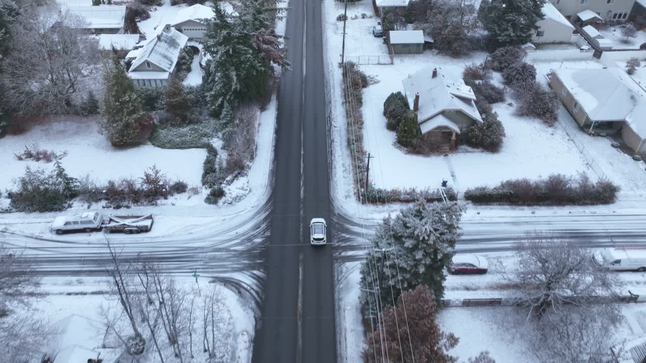 vista aérea de arriba hacia abajo de un automóvil que viaja a través de un vecindario lleno de nieve