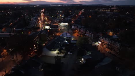 tiro de establecimiento aéreo de la bifurcación de la calle iluminada con coches de conducción por la noche. casas en el área de vivienda estadounidense durante la noche clara de invierno. drone creciente tiro ancho.