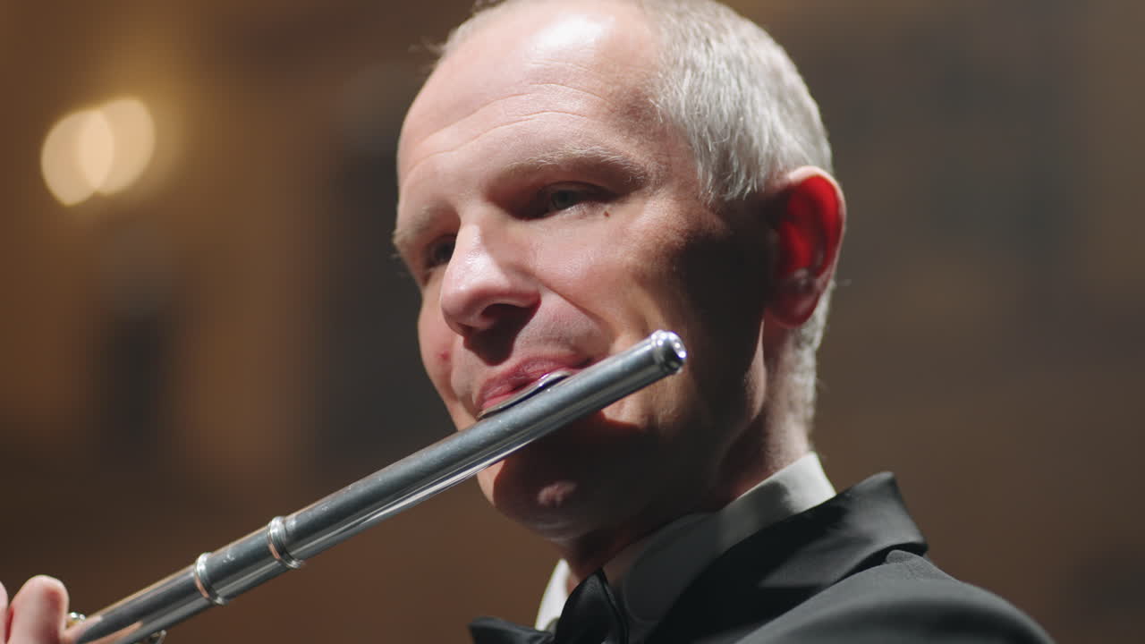 중년 플루티스트가 플루트를 연주하고 있습니다. 오래된 오페라 하우스에서 콘서트에서 뮤지션의 초상화 촬영