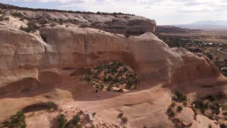 people admiring panorama from wilson arch rock formation,utah