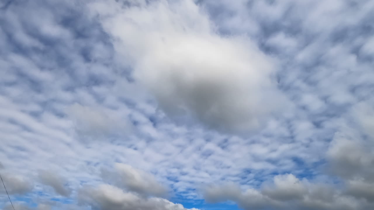 Cirrocumulus and cumulus clouds floating in the atmosphere. Cloudscape fly away and the sky is clearing up. Low angle view. Timelapse.