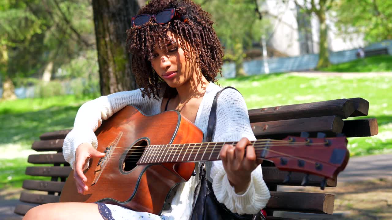Kvinde spiller guitar i parken
